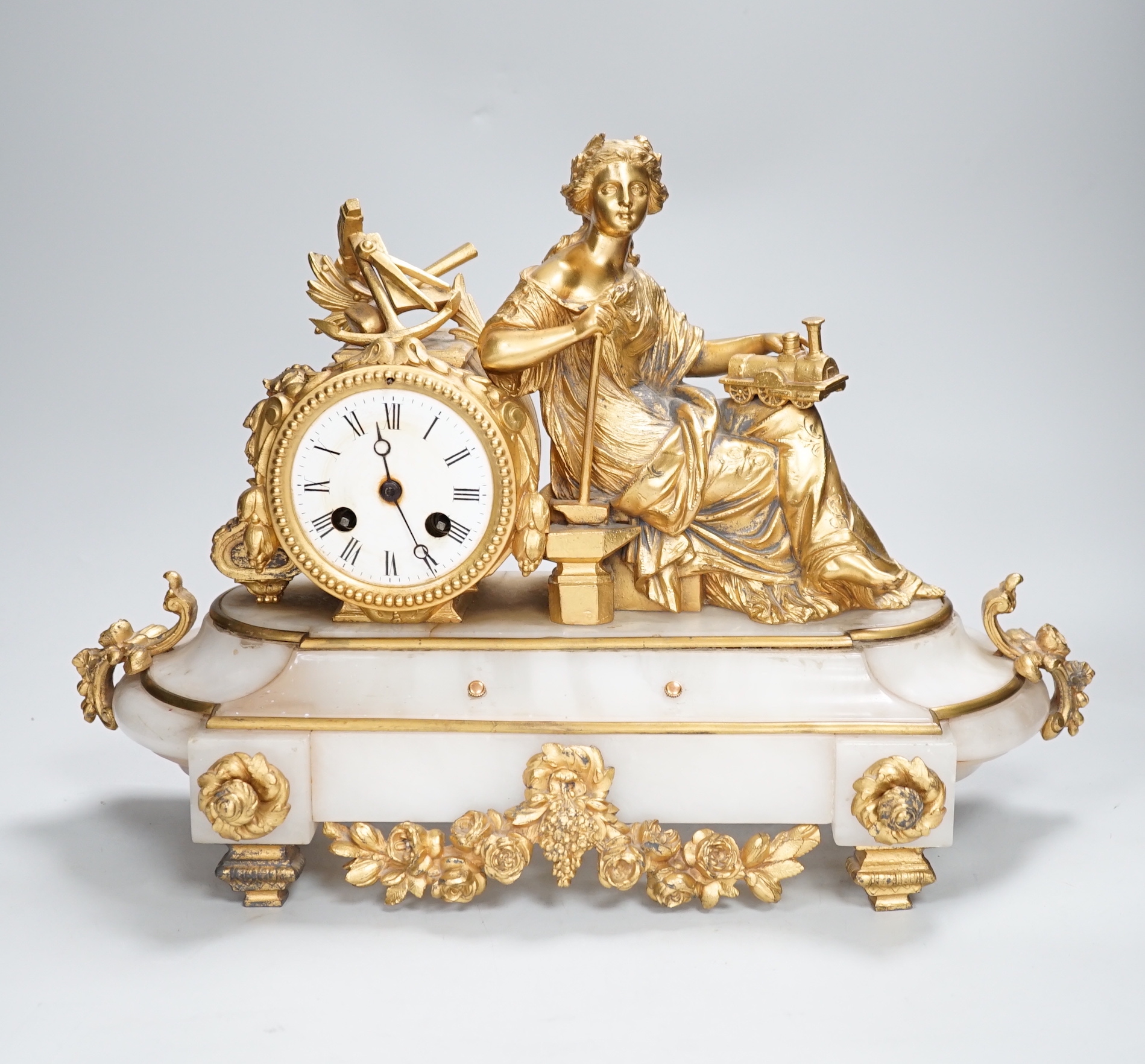 A late 19th century French gilt metal and onyx clock mounted with the figure of Industry holding a locomotive, 42cm wide